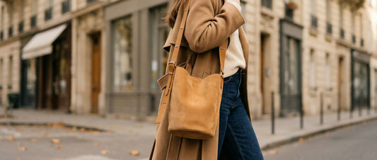 Femme portant un sac seau femme en daim camel en bandoulière dans une rue parisienne en automne