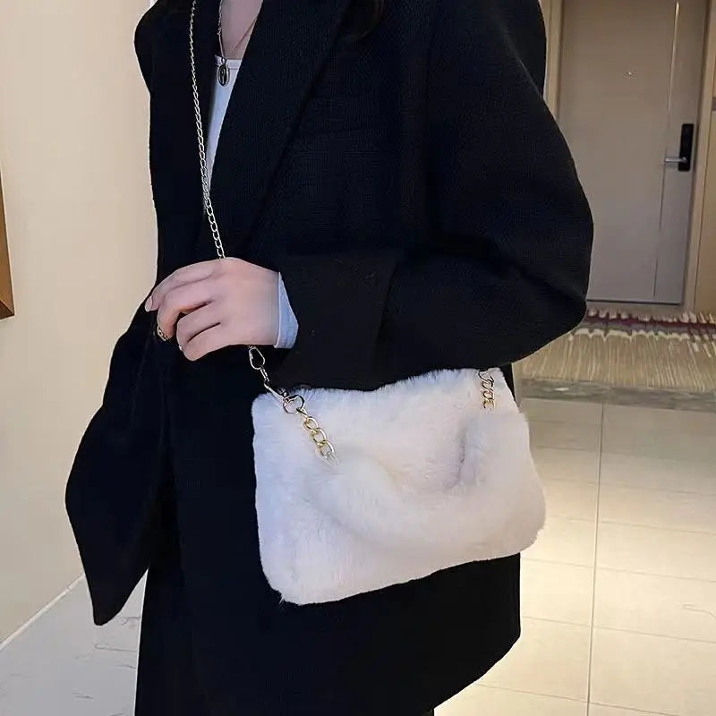 Sac à Main Fausse Fourrure Doux et Élégant, de couleur blanche, avec une chaînette dorée, porté par une femme en bandoulière avec une veste noire.
