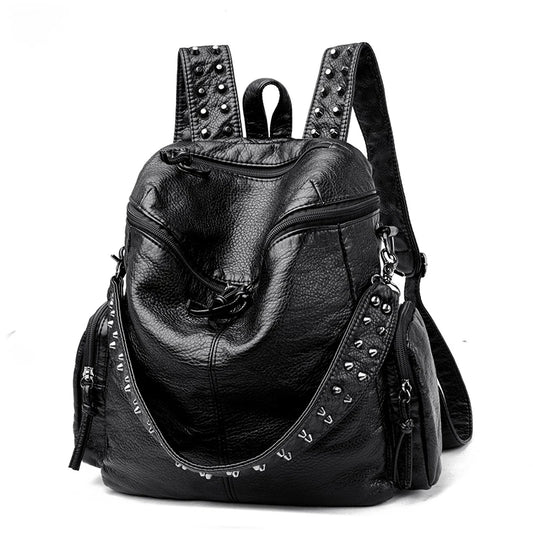 Sac à Main et à Dos Femme Tendance en Simili, de couleur noire, avec décorations à rivets sur les bretelles, sur un fond blanc.