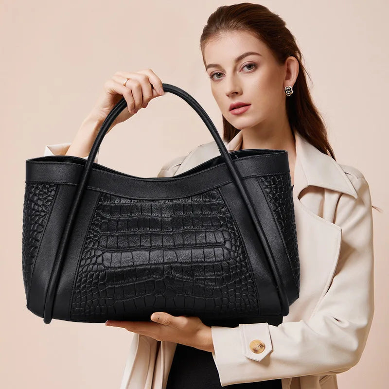 Sac à Main en Cuir Femme Grand Format Noir, avec des formes d'écailles, dans les bras d'une femme sur un fond rosé.
