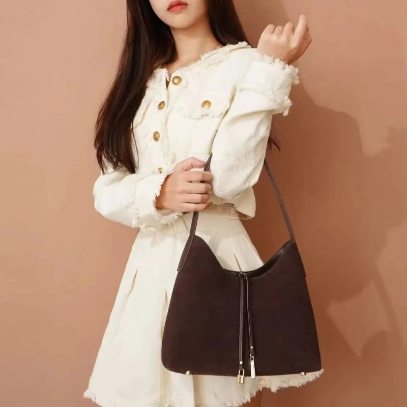 Sac à Main Baguette Marron Fourre Tout, porté par une femme en tenue blanche, sur un fond orange.
