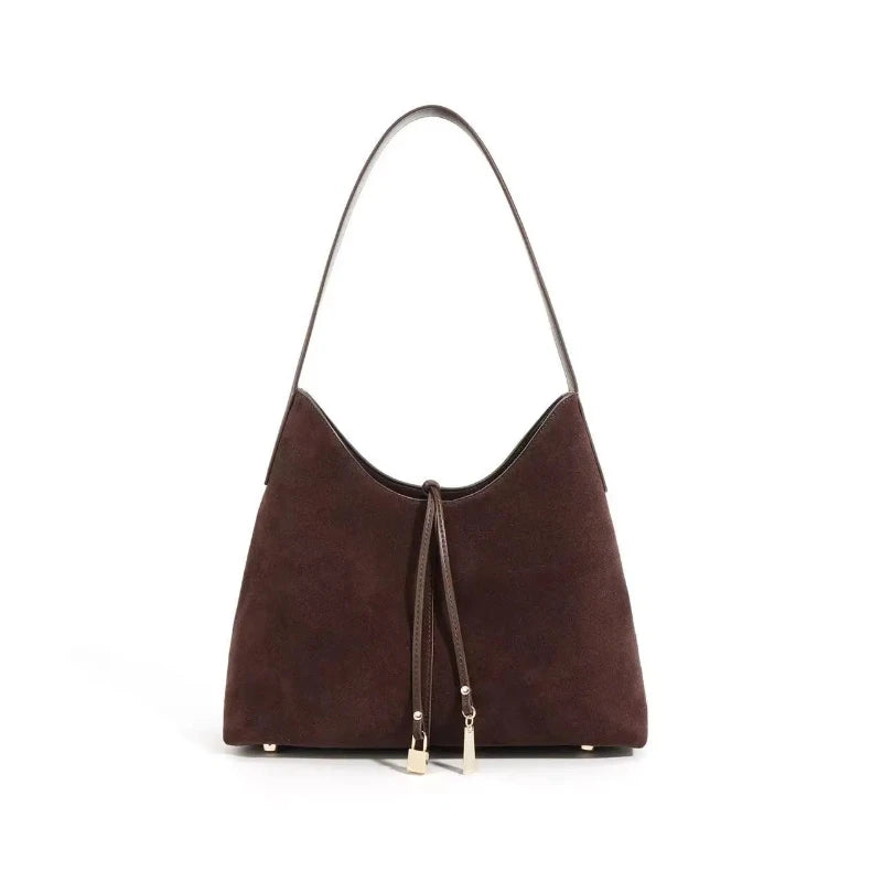 Sac à Main Baguette Marron Fourre Tout, avec deux pendentifs, sur un fond blanc.