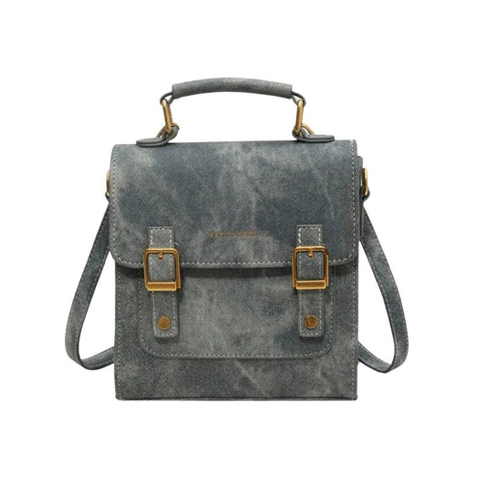 Sac Cartable Femme Bleu Design Élégant, de couleur bleu, avec des boucles de fermetures dorées sur un fond blanc.